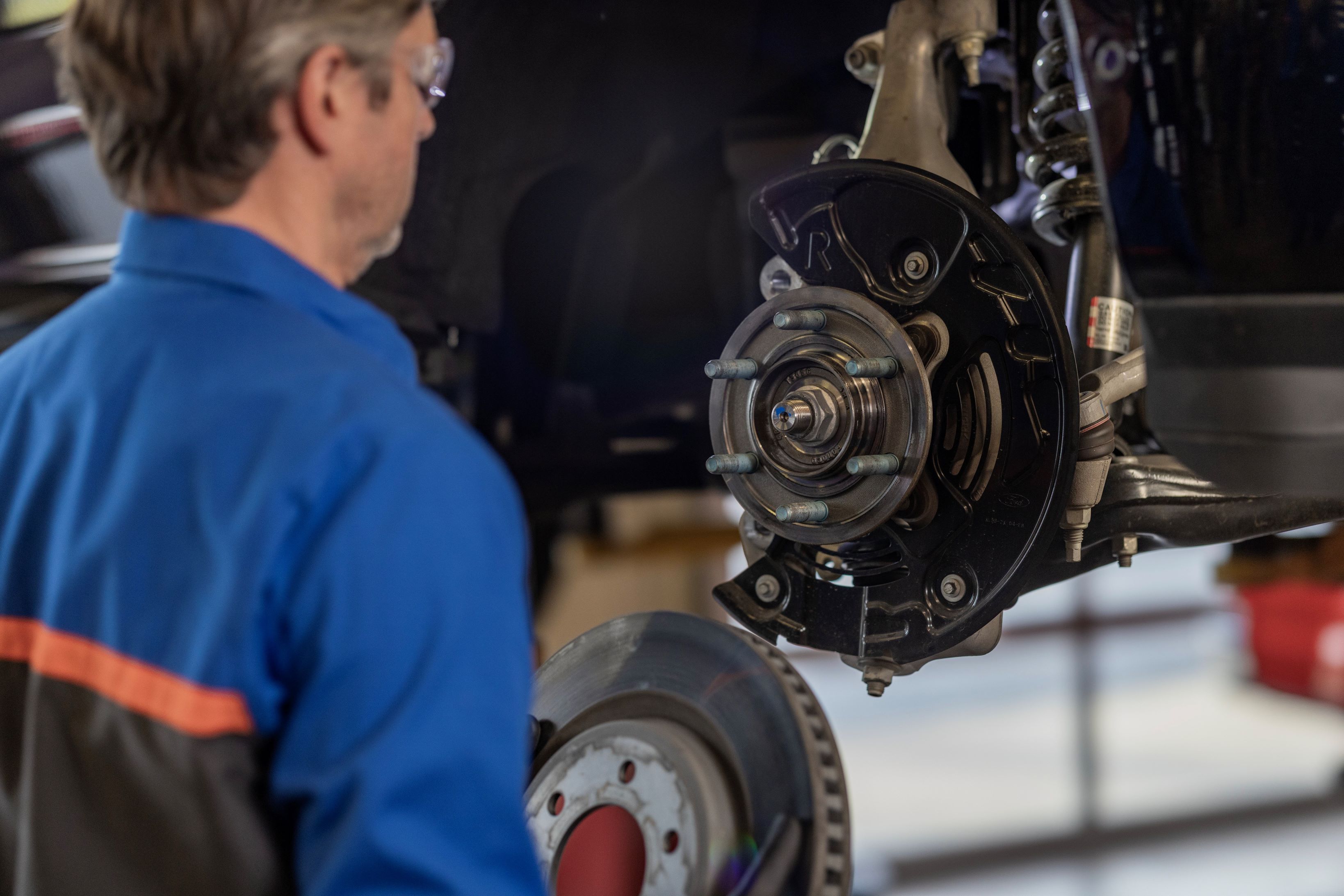 A vehicle technician installs brakes.